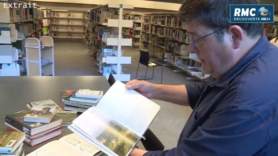 Daniel Tardy consultant des ouvrages en bibliothèque, extrait RMC Découverte